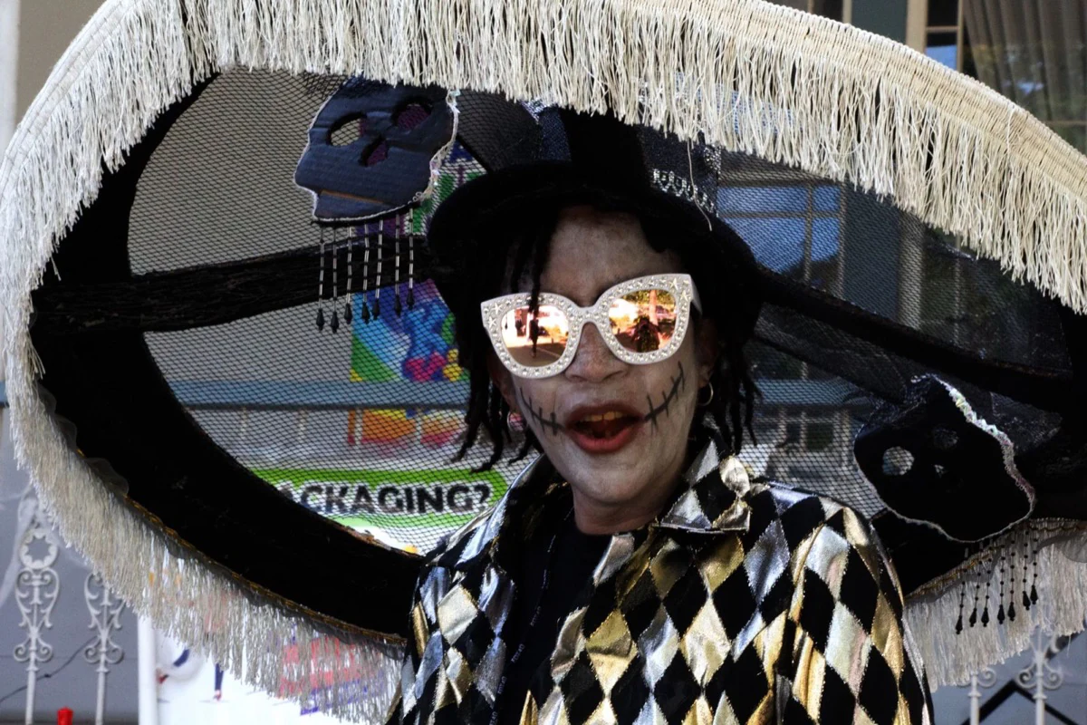 A harlequin performer smiling beneath an elaborate costume
