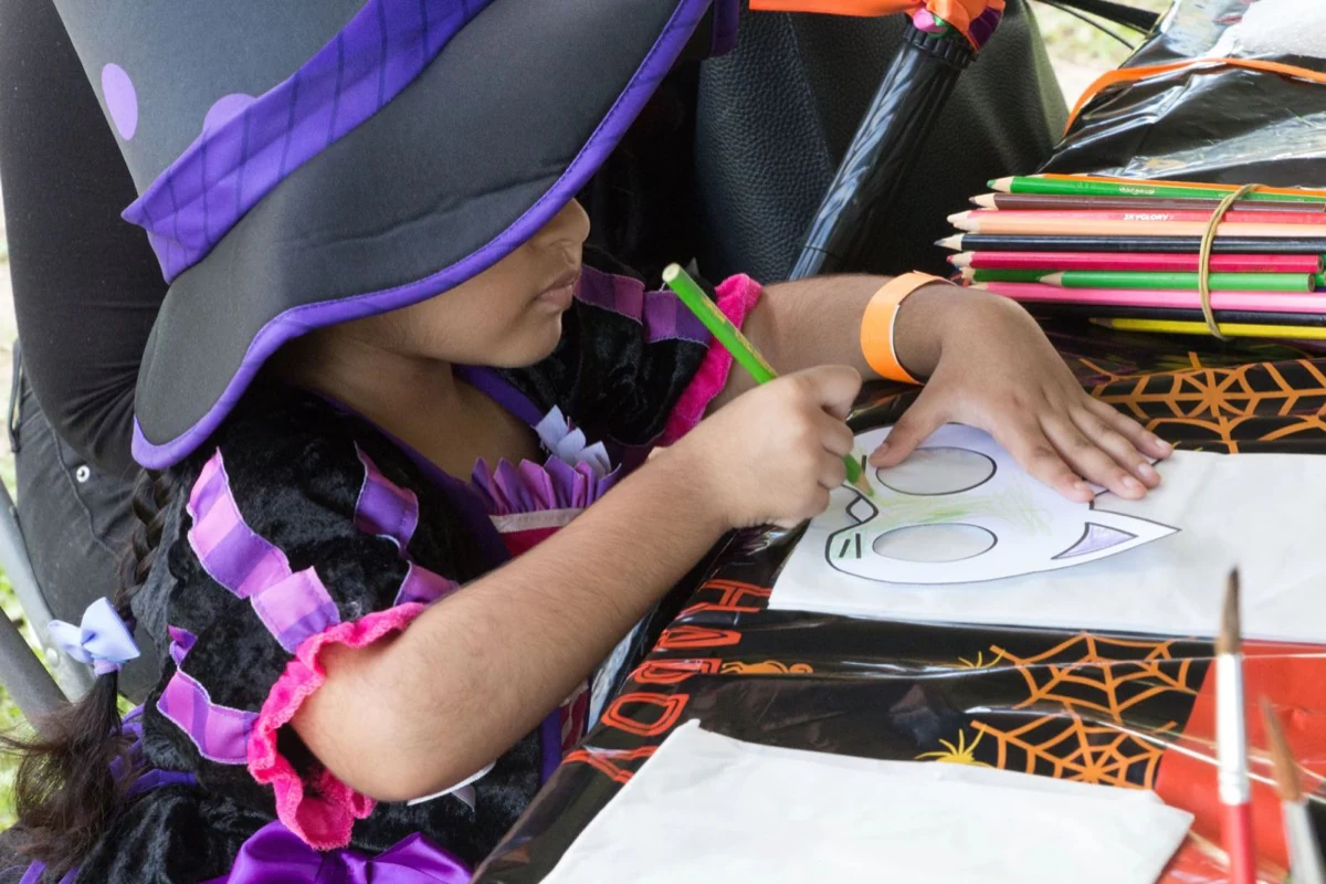 A child in a witch costume drawing at the creative activity table