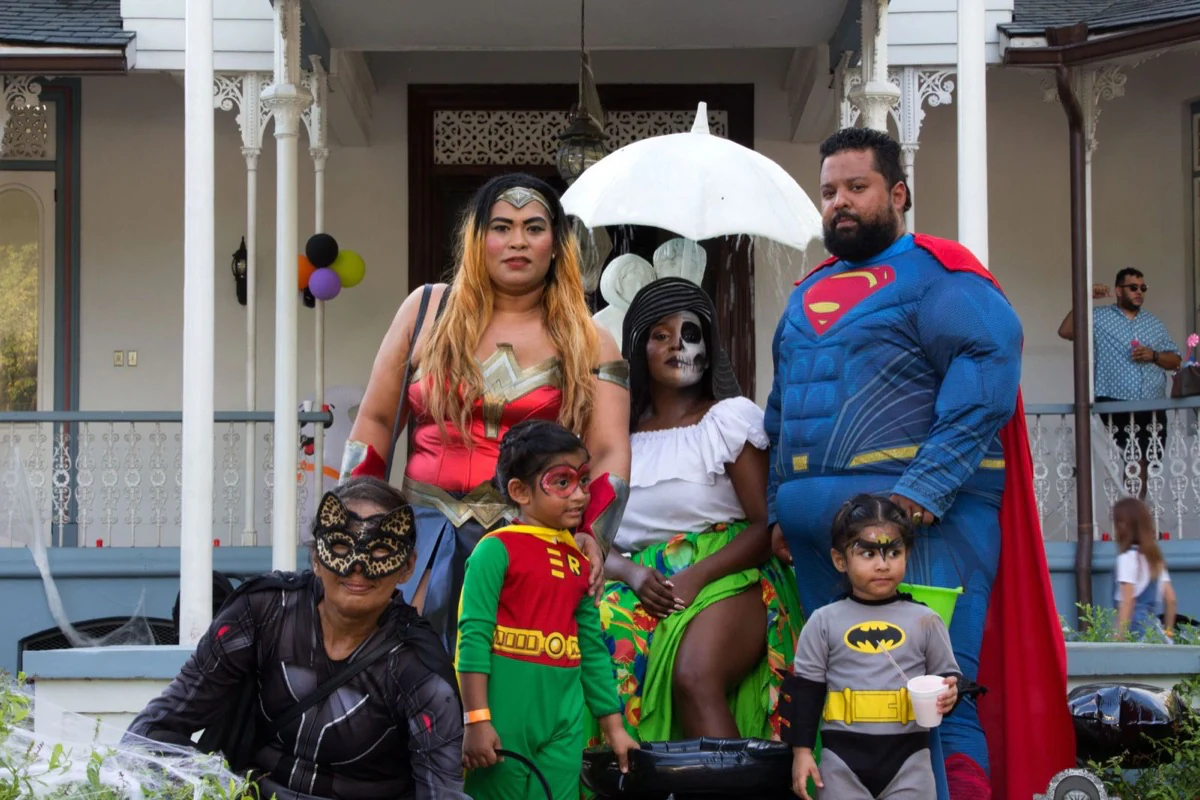 A family posing together in colourful superhero costumes