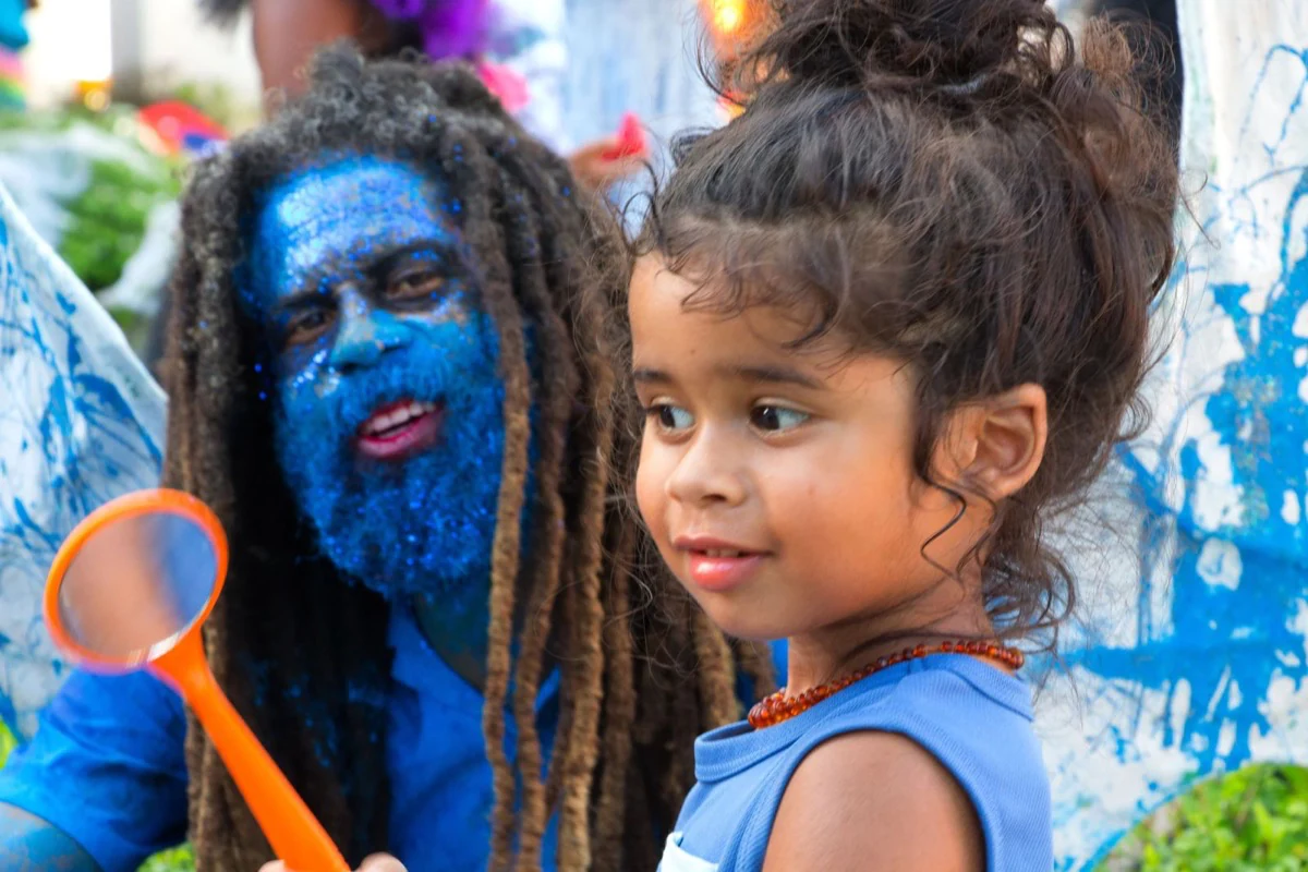 A young child discovering bubbles with a blue costumed performer