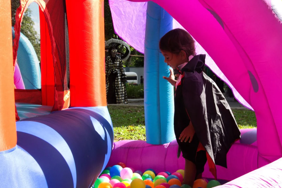 A child dressed in a cape playing inside a bright bounce house