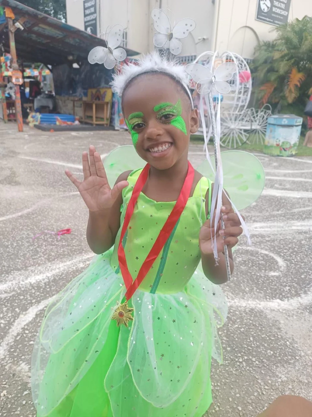 A smiling child dressed as a green fairy