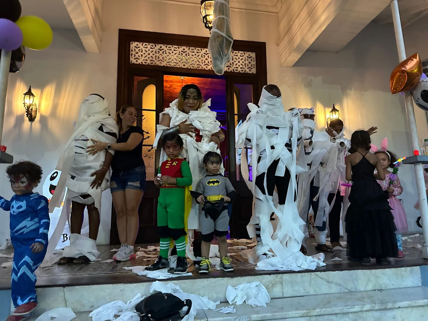 Families and children taking part in a playful mummy wrapping game